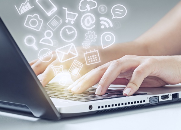woman typing on laptop and media icons fly off woman typing on laptop computer and media app icons flying. There is a warm glow on fingers.